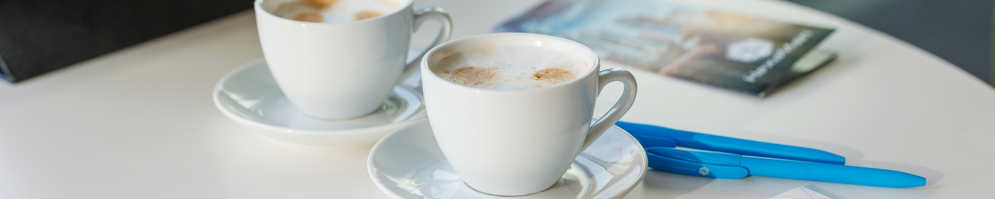 Partner-Hero-Image HexaMain Partner Hero Image – Bild, das zwei Cappuccinos und die Unternehmensbroschüre zeigt, symbolisierend Partnerschaft und professionelle Zusammenarbeit.